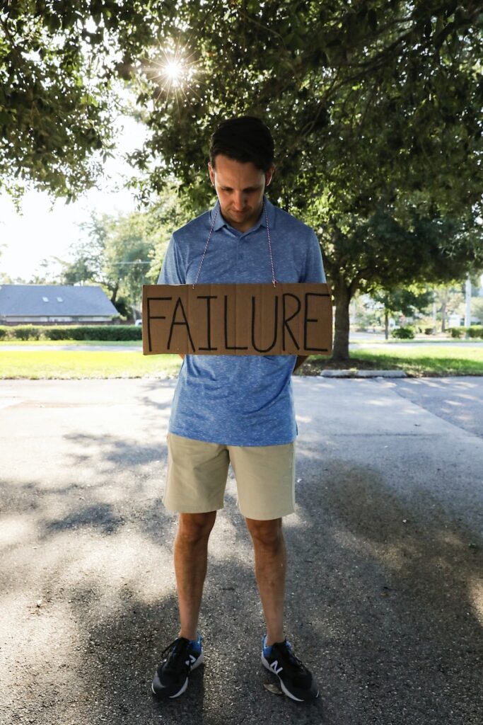 man in blue and white crew neck t-shirt holding brown wooden signage