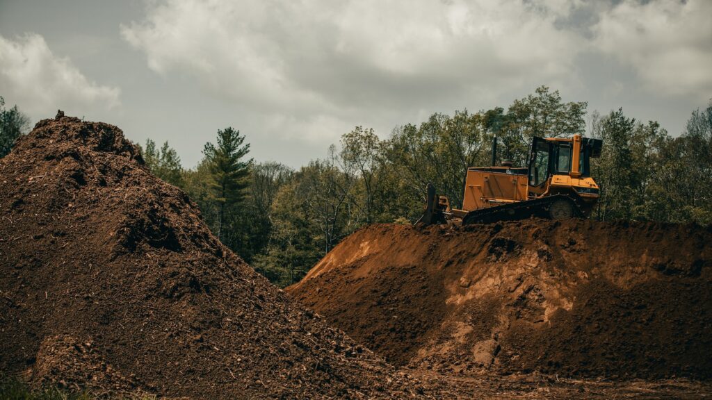 yellow and black heavy equipment on brown rocky hill under white cloudy sky during daytime